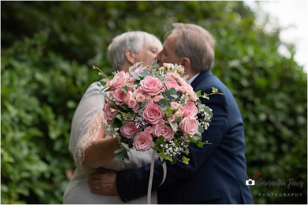 bride and groom kissing behind bouquet wedding Kent 2020